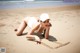 A woman laying on the beach writing in the sand.