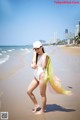 A woman in a white bathing suit standing on a beach.