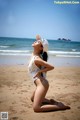 A woman in a white bathing suit and hat on the beach.