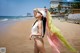 A woman in a white bathing suit and hat on a beach.