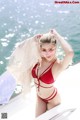 A woman in a red bikini standing on a boat.