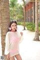 A woman standing next to a palm tree on a beach.