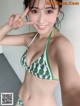 A woman in a green and white bikini posing for a picture.