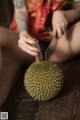 A woman cutting a durian with a knife.