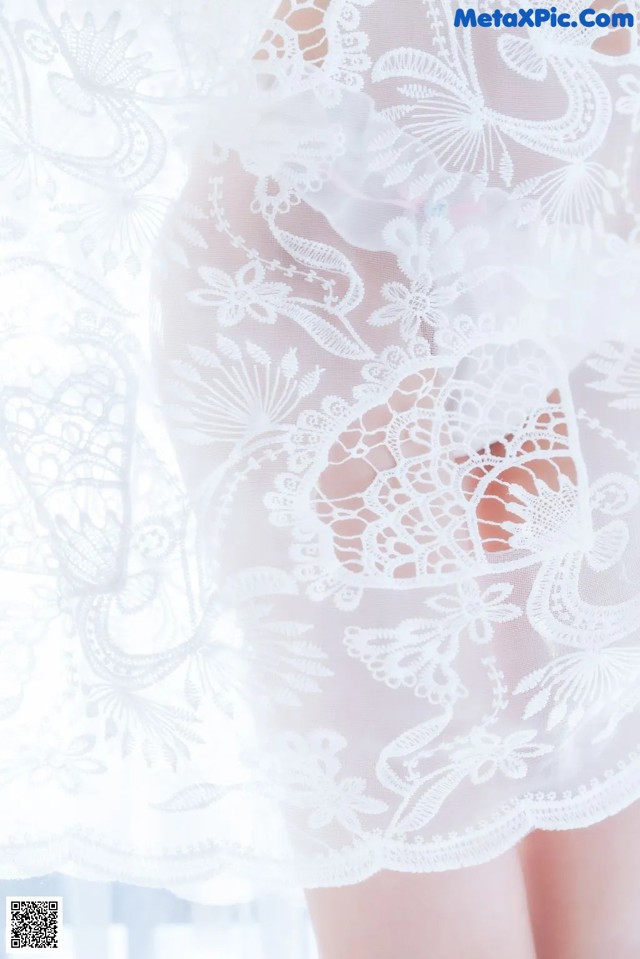 A close up of a woman wearing a white lace robe.