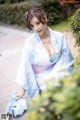 A woman in a blue kimono sitting on the ground.