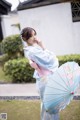 A woman in a blue kimono holding a blue umbrella.