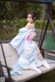 A woman in a blue and white kimono sitting on a swing.