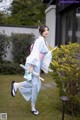 A woman in a blue kimono holding an umbrella.