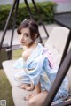 A woman in a blue and white kimono sitting on a chair.