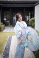 A woman in a blue kimono holding an umbrella.