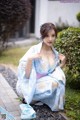 A woman in a blue and white kimono sitting on the ground.