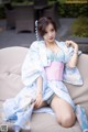 A woman in a blue and pink kimono sitting on a couch.