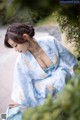 A woman in a blue and white kimono sitting on the ground.