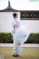 A woman in a blue kimono holding an umbrella.