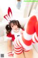 A woman in a red and white bunny costume laying on a bed.