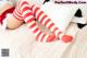 A woman wearing red and white striped stockings laying on a bed.