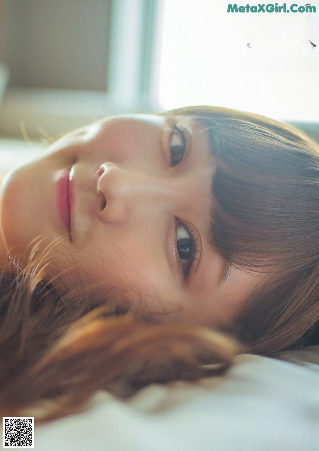 A woman laying on top of a bed next to a window.