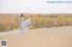 A woman in a long dress standing on top of a sand dune.