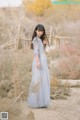 A woman in a long blue dress standing in a field.