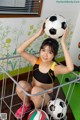 A young woman holding a soccer ball over her head.