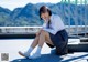 A woman in a school uniform sitting on a ledge.