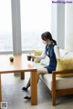 A woman sitting on a couch with a cup of coffee.