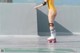 A woman in a yellow bodysuit is rollerblading on a skateboard.