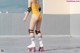 A woman in a yellow bathing suit on roller skates.