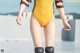 A woman in a yellow and black one piece swimsuit and knee pads.