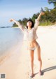 A woman standing on a beach with her arms outstretched.