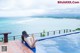 A woman in a white bikini sitting on the edge of a swimming pool.