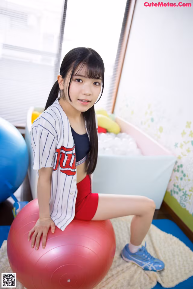 A young woman sitting on an exercise ball in a room.