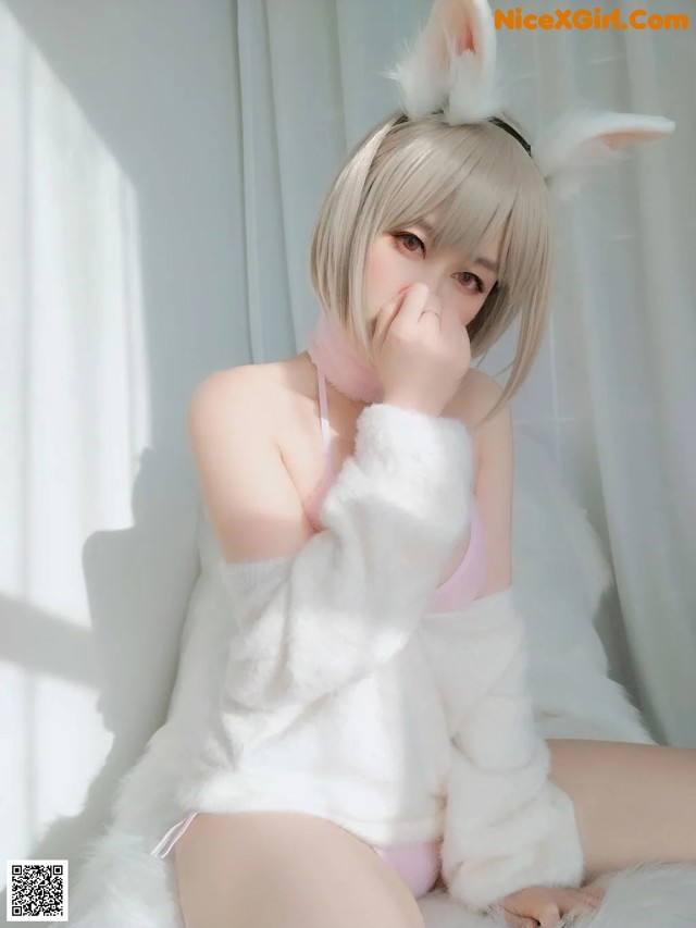 A woman in a bunny costume sitting on a bed.