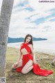 A woman in a red dress sitting under a palm tree.