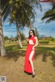 A woman in a red dress standing in the grass.