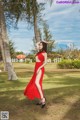 A woman in a red dress standing in the grass.