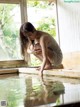 A woman kneeling on the edge of a pool of water.