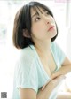 A woman in a blue shirt is looking up at the sky.