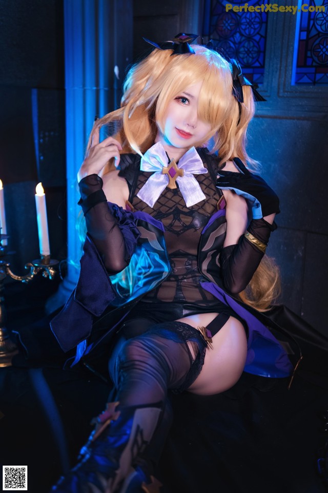 A woman in a black and blue outfit sitting on a chair.