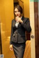 A woman in a business suit holding a glass of wine.