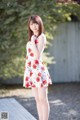 A woman in a white dress with red flowers on it.