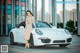 A woman standing next to a white car in a parking lot.