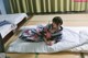 A woman in a kimono sitting on a bed in a room.