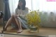 A woman sitting on the floor next to a vase of flowers.