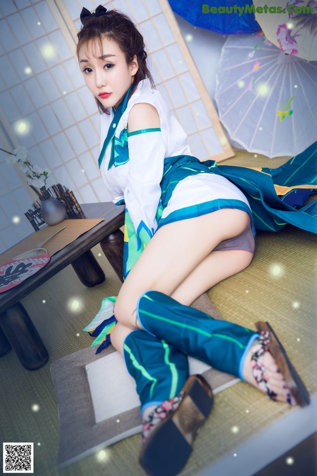 A woman in a blue and green outfit sitting on a table.