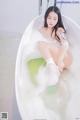 A woman sitting in a bathtub filled with foam.