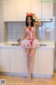 A woman in a red and white nurse outfit posing in a kitchen.