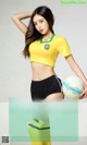 A woman in a yellow shirt holding a soccer ball.