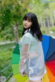 A woman in a white shirt holding a colorful umbrella.